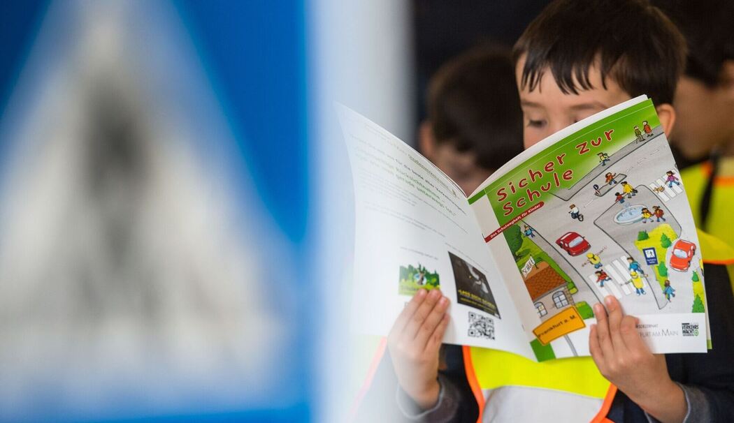 Ein Junge hält die Broschüre "Sicher zur Schule"