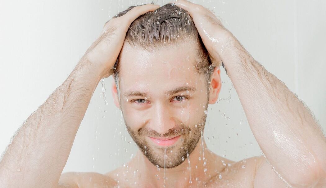 Mann steht unter einer Dusche