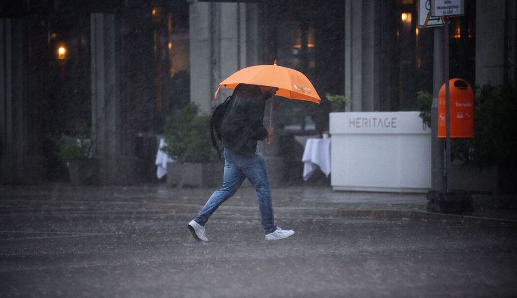 Ein Mann mit Regenschirm im Starkregen