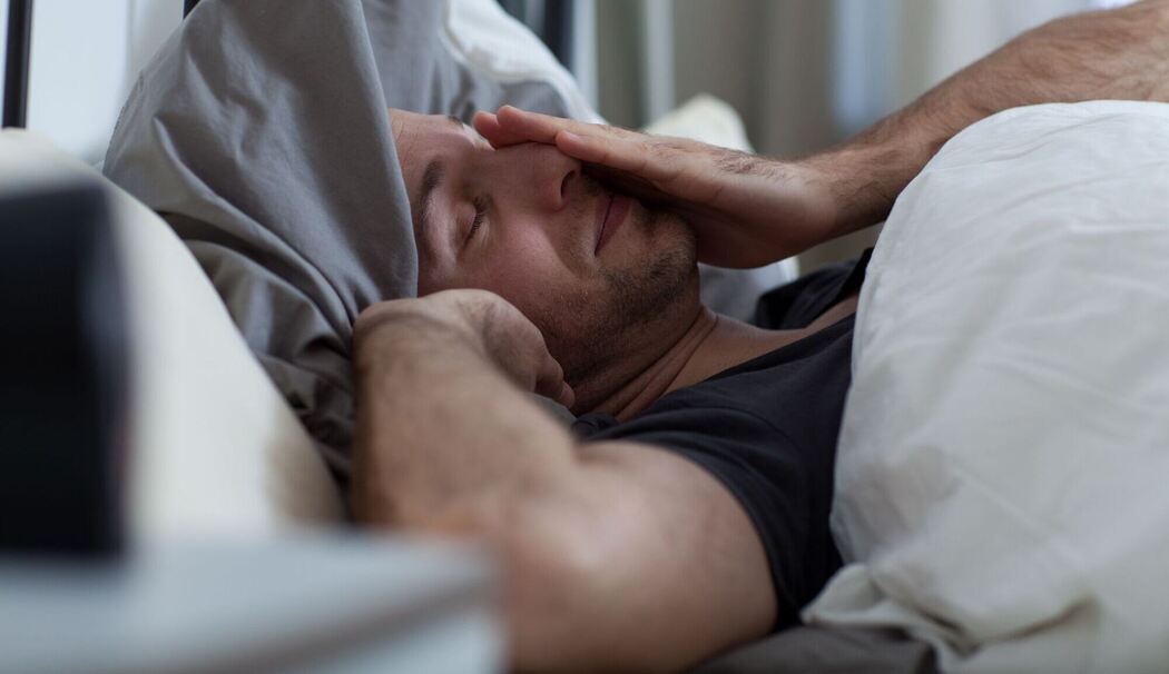 Ein Mann liegt mit Schlafstörungen im Bett