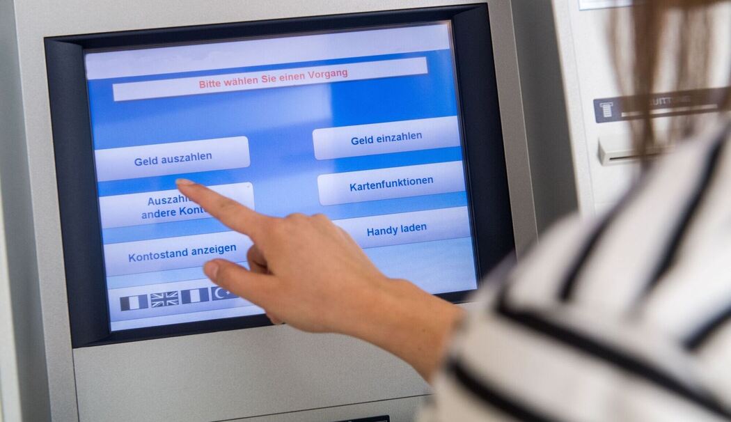 Frau hebt Geld an einem Automaten ab