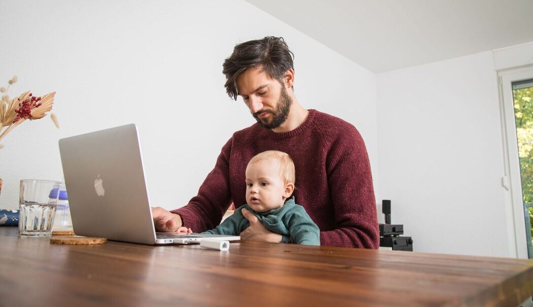 Mann mit Kleinkind im Homeoffice