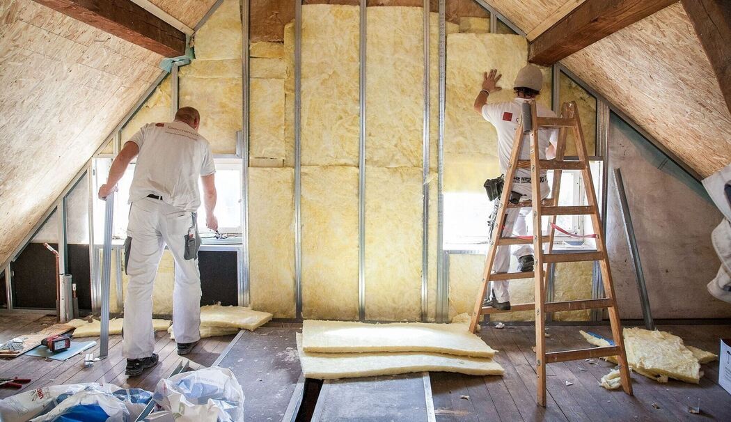 Zwei Handwerker dämmen ein Dachgeschoss