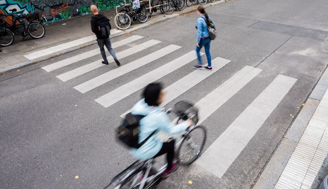 Radfahrer und Fußgänger überqueren einen Zebrastreifen