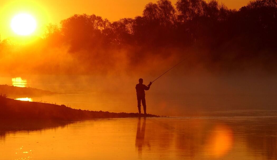 Angler wirft im Licht der Morgensonne seinen Köder aus