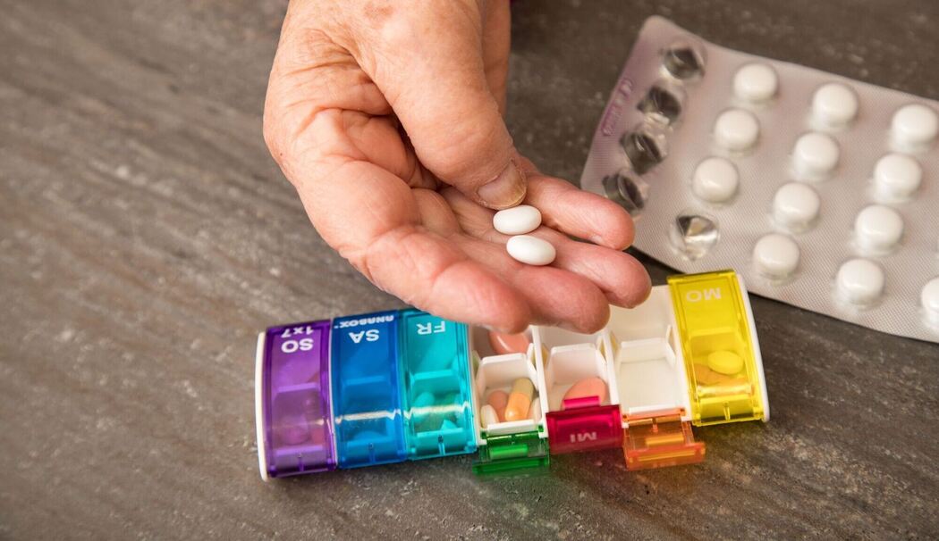 Seniorin nimmt Tabletten aus einer Pillendose