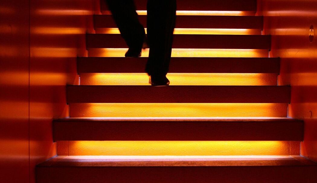 Mann geht eine angeleuchtete Treppe hinab