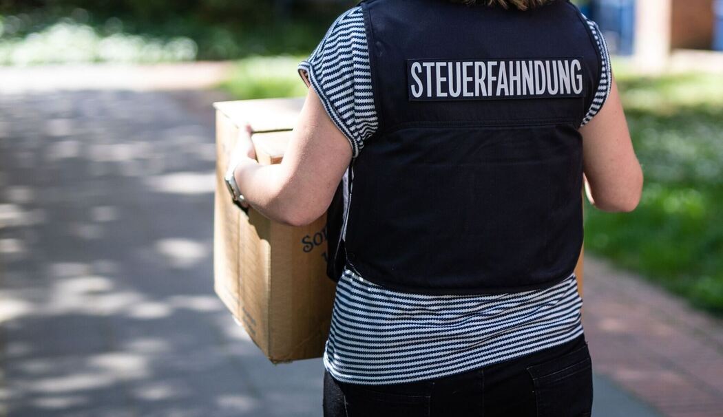 Mitarbeiterin der Steuerfahndung trägt beschlagnahmte Unterlagen