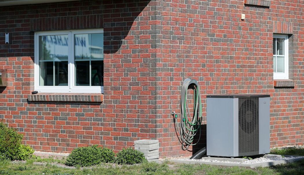 Eine Luft-Wasser-Wärmepumpe steht vor einem Haus
