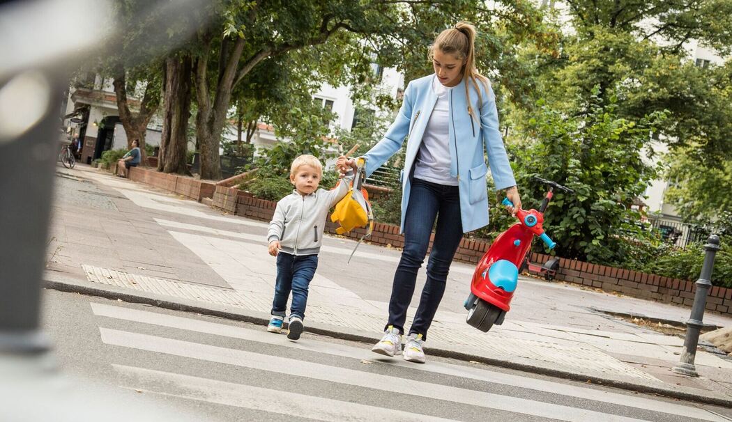 Frau geht mit ihrem Kind über eine Straße