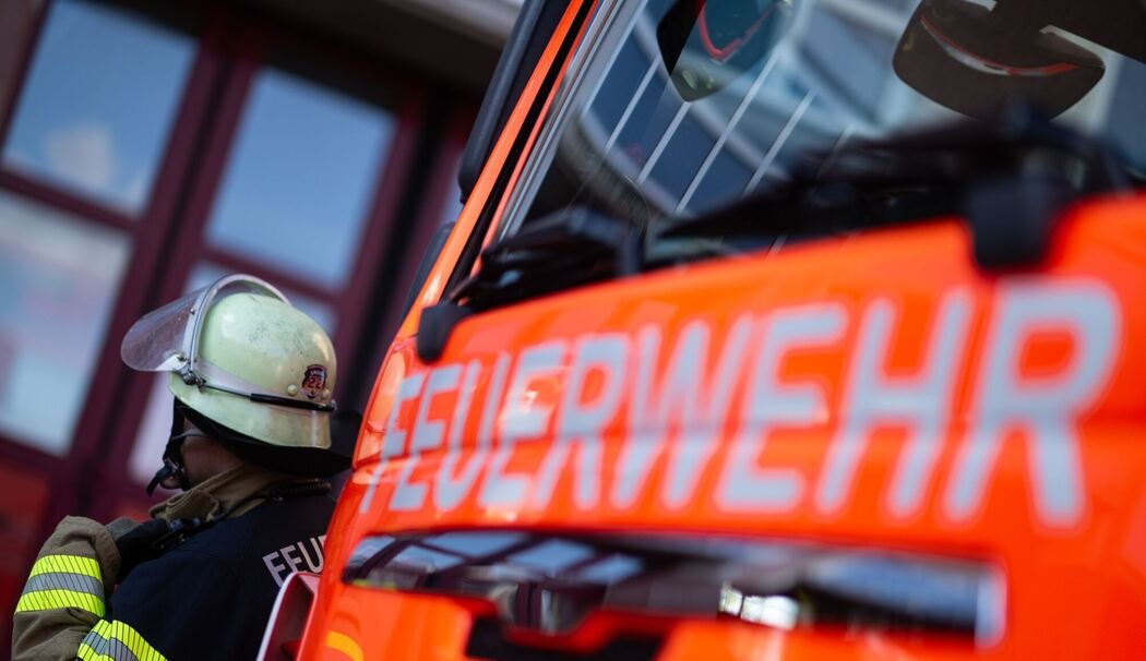 Feuerwehrmann steht neben einem Feuerwehrauto (Symbolbild)