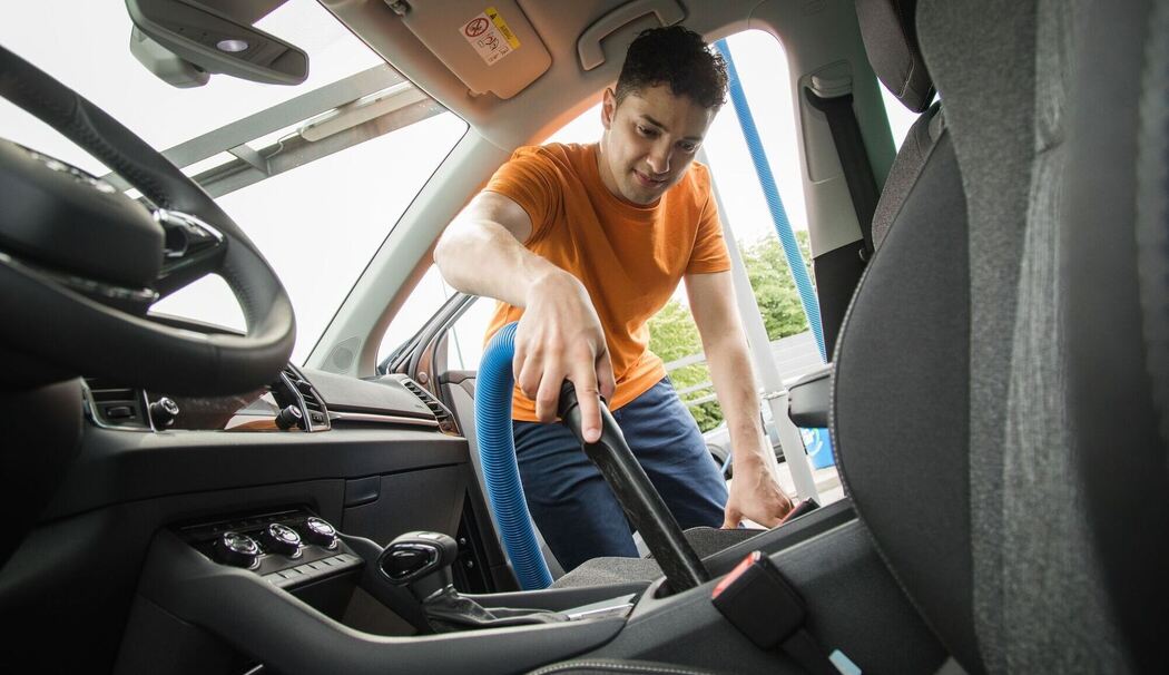Mann saugt den Innenraum seines Autos