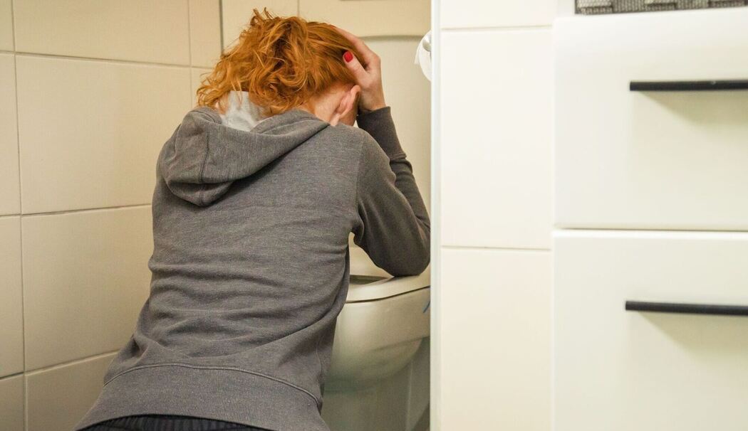 Frau kniet vor einer Toilette