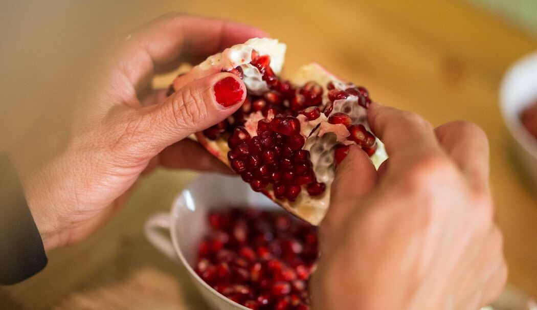 Frau schält einen Granatapfel