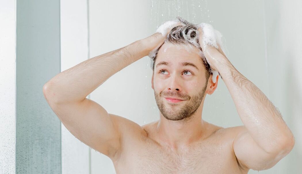 Mann wäscht sich unter der Dusche die Haare
