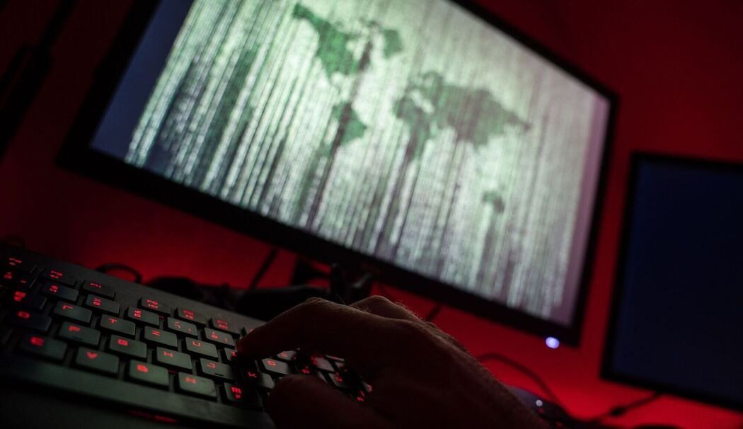 Person sitzt am Rechner und tippt auf einer Tastatur