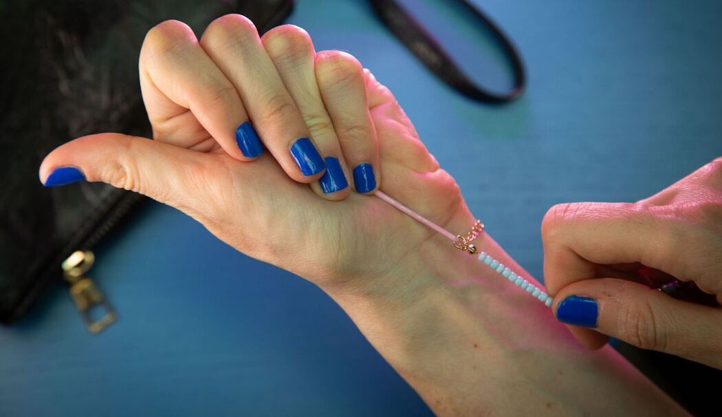 Frau legt Armband mit Hilfe einer Haarnadel an