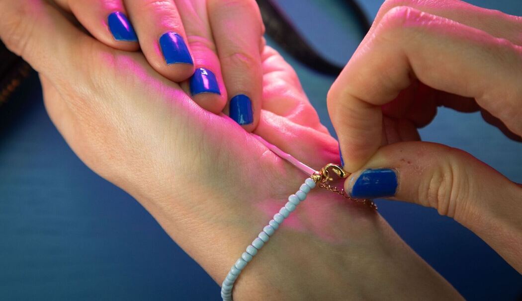 Frau legt Armband mit Hilfe einer Haarnadel an
