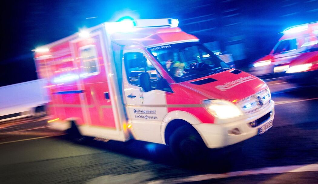 Rettungswagen der Feuerwehr fährt mit Blaulicht durch eine Straße