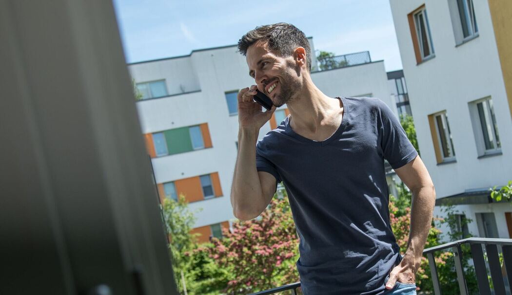 Mann telefoniert auf einem Balkon
