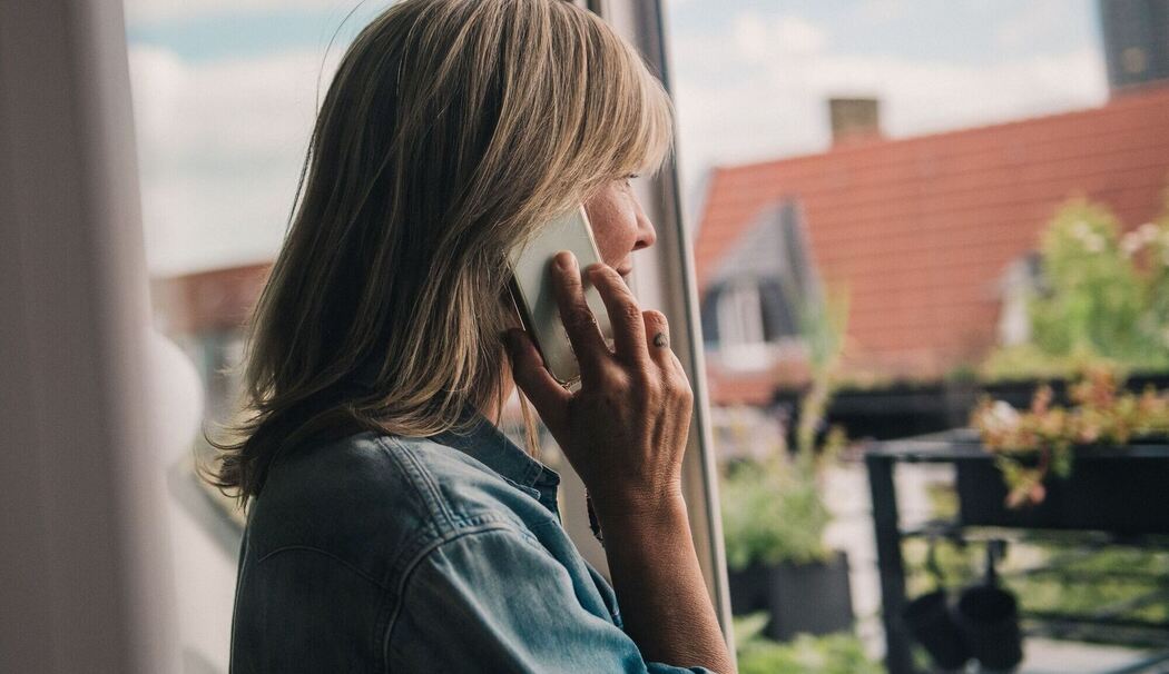 Eine Frau telefoniert am Fenster