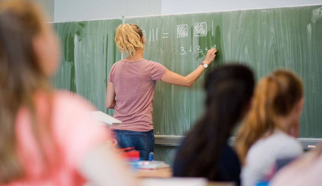 Lehrerin schreibt im Mathematikunterricht an eine Schultafel