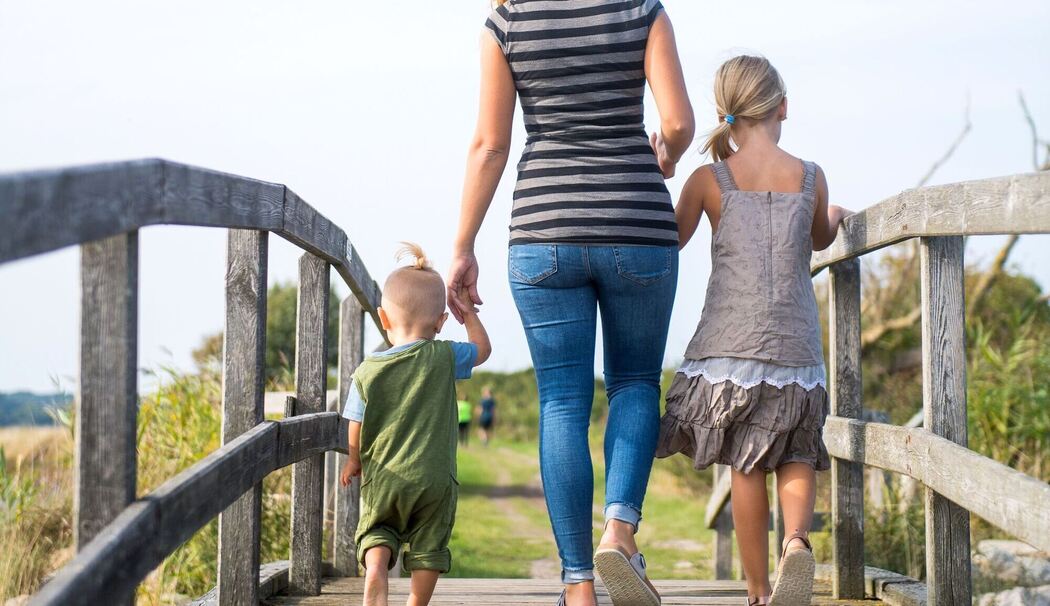 Eine Mutter läuft mit ihren Kindern über einen Steg