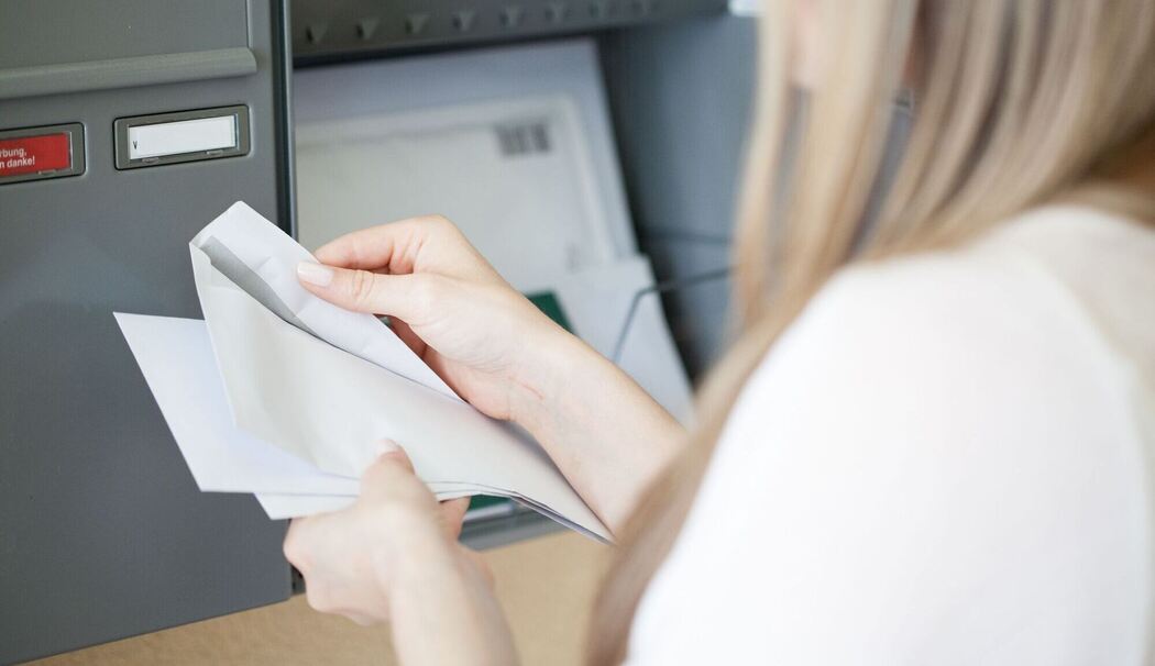 Eine Frau holt Post aus dem Briefkasten