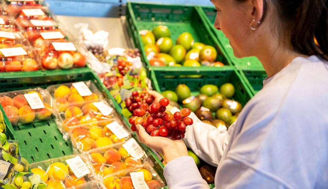 Eine Frau begutachtet Trauben in einem Supermarkt
