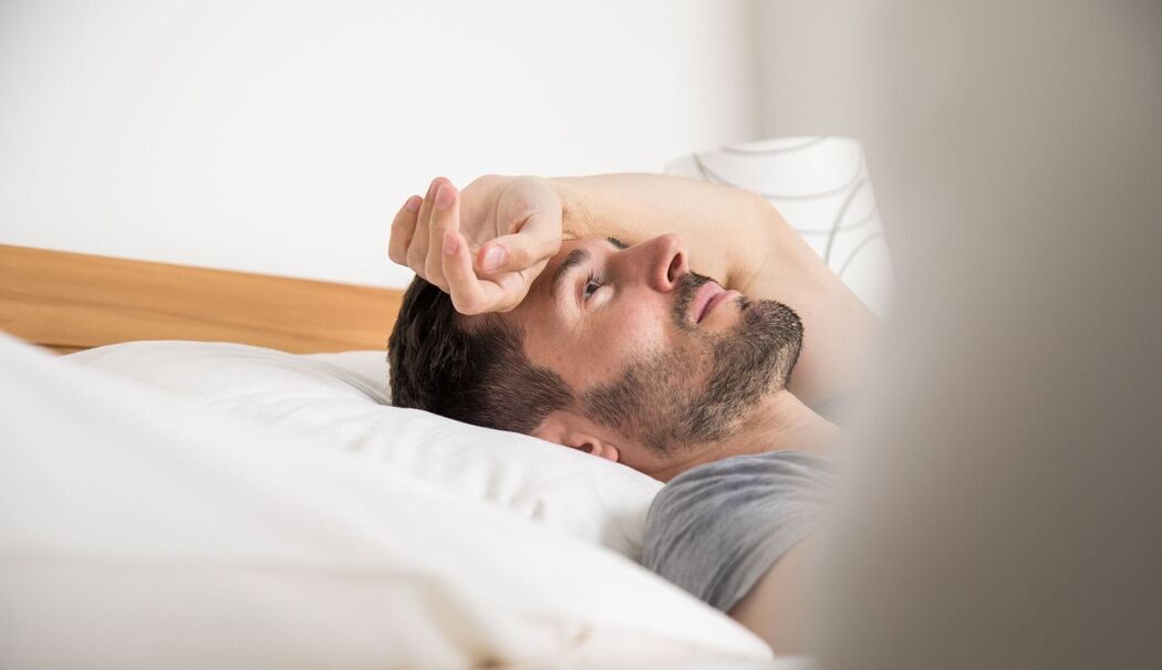 Mann liegt schlaflos im Bett