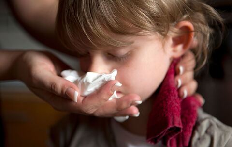 Ein Kind mit Nasenbluten hat Handtuch im Nacken