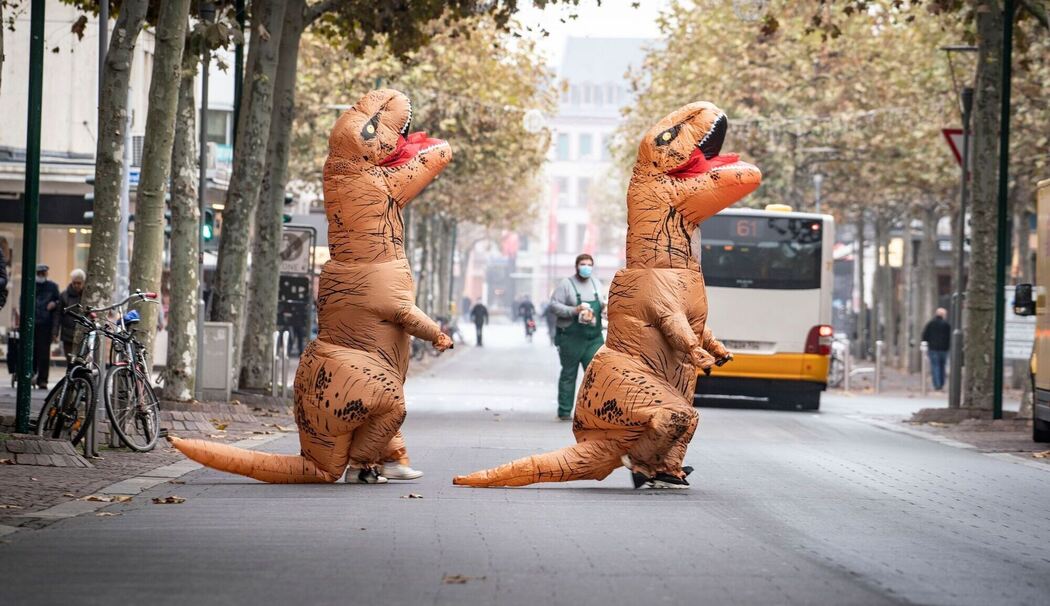 Karnevalistinnen in aufblasbaren Dinosaurier-Kostümen