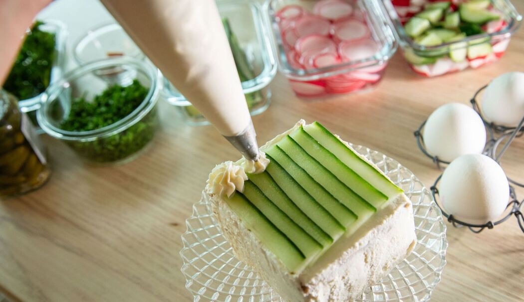 Brottorte wird mit Frischkäse und Gurke dekoriert