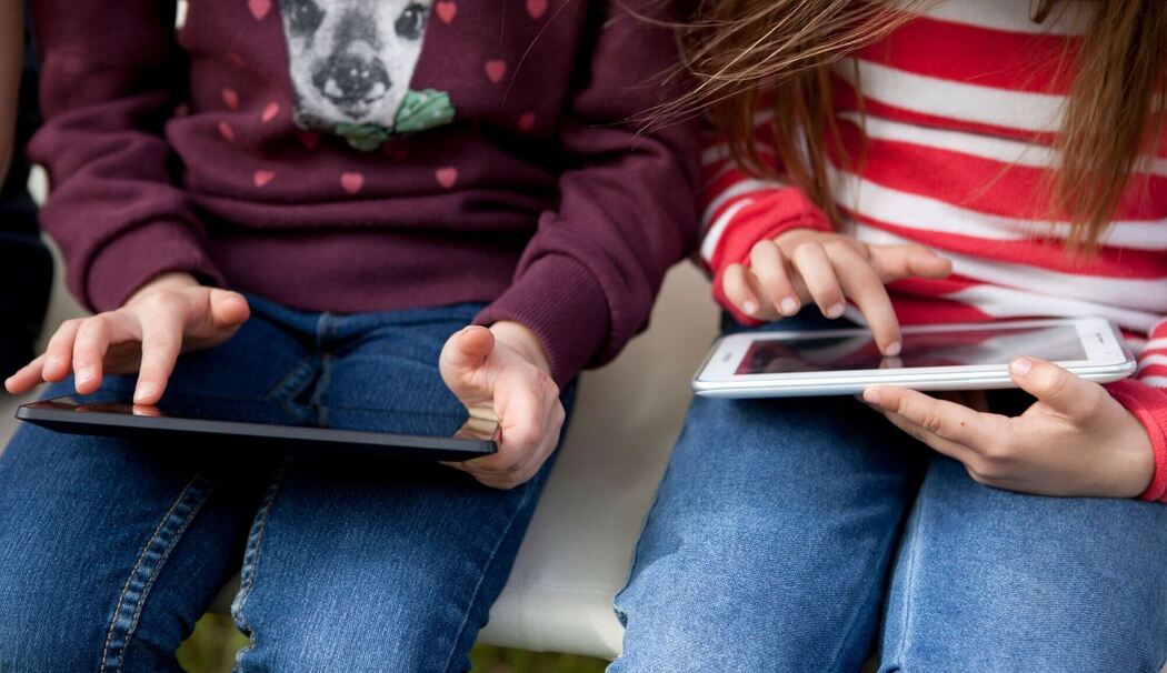 Zwei Kinder spielen etwas auf ihren Tablets