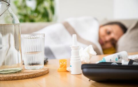 Eine Frau liegt mit einer Erkältung auf dem Sofa