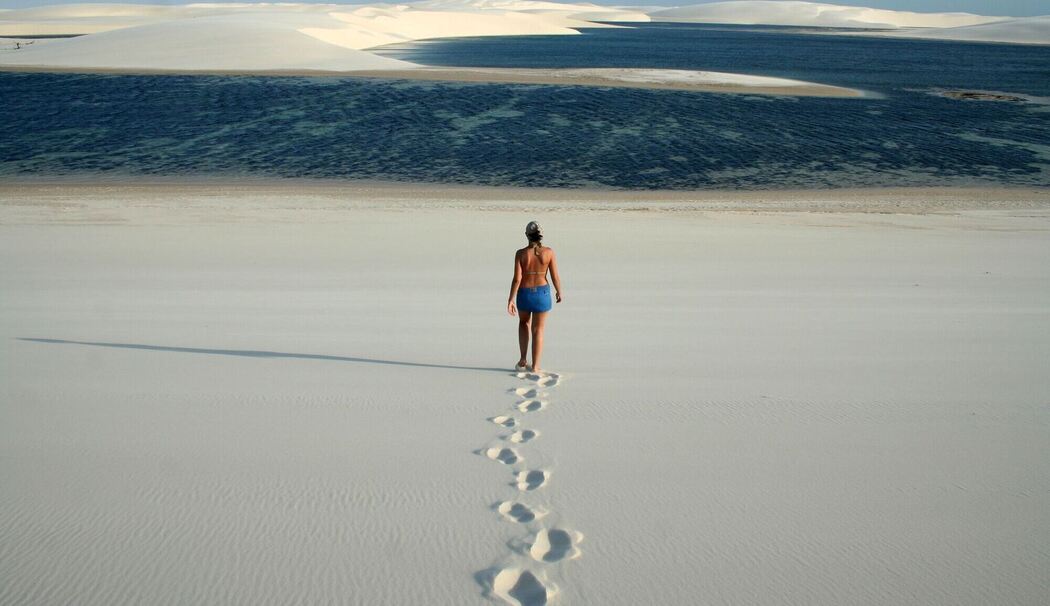 Frau läuft durch Dünenlandschaft zu einer kleinen Lagune
