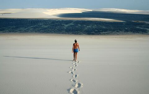Frau läuft durch Dünenlandschaft zu einer kleinen Lagune
