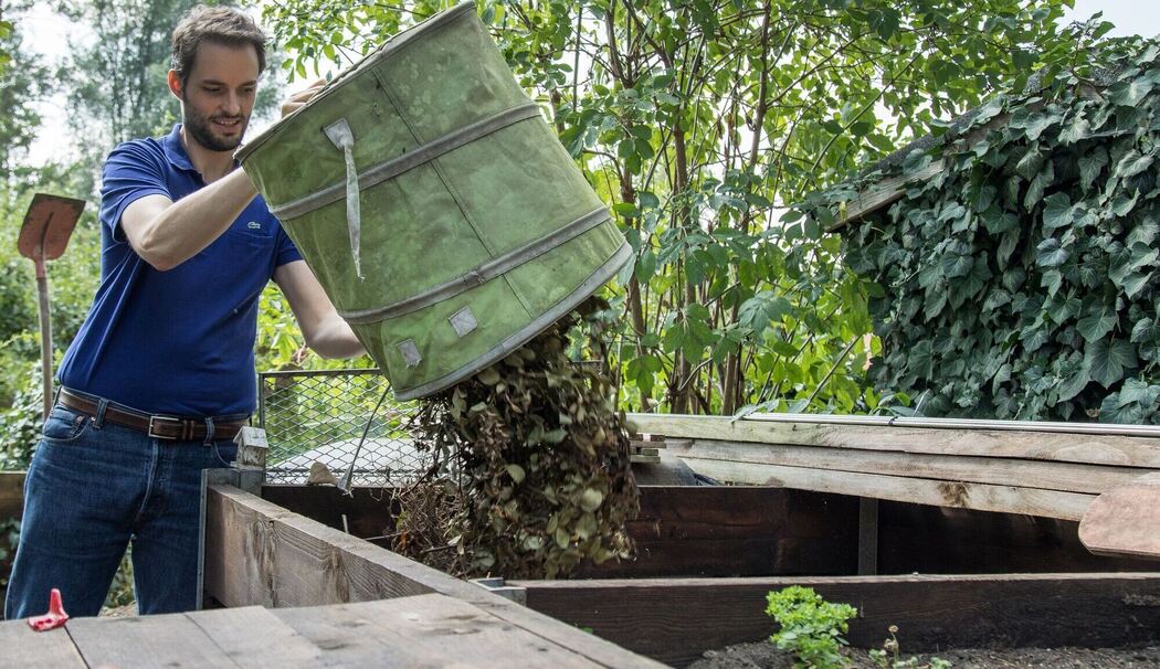 Mann entsorgt Pflanzenreste auf dem Kompost