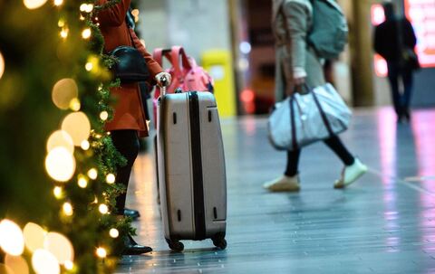 Eine Frau steht bei ihrem Gepäck in einem Bahnhof