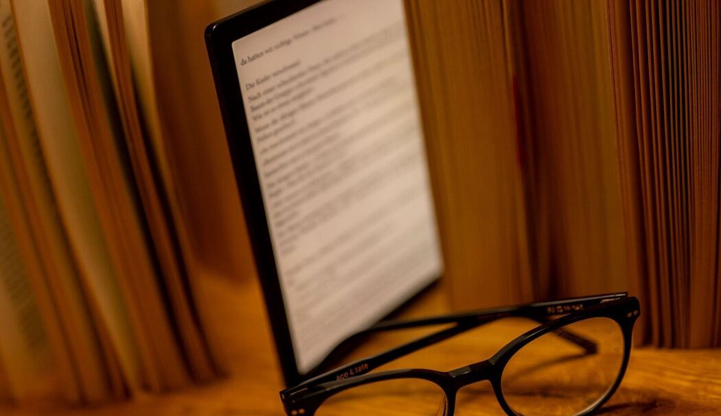 E-Book-Reader steht zwischen Büchern auf einem Tisch