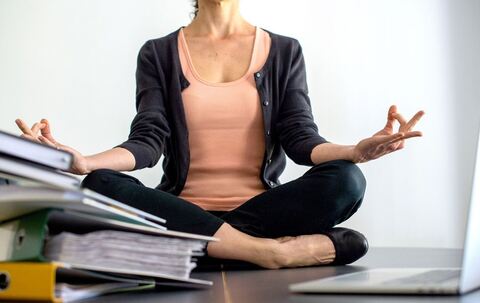 Eine Frau sitzt im Schneidersitz auf einem Schreibtisch