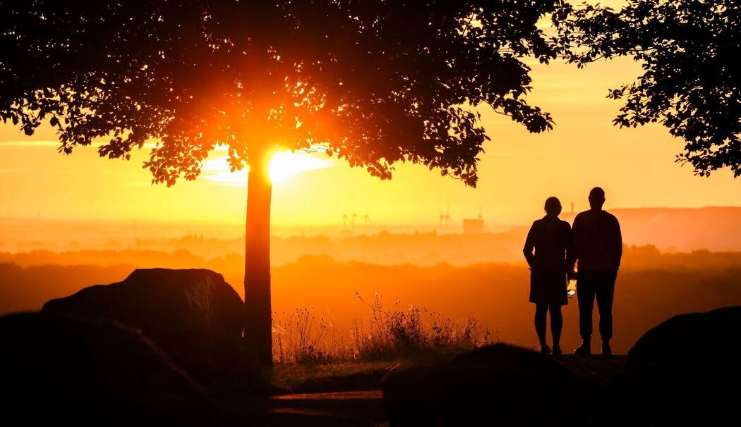 Ein Paar steht bei Sonnenaufgang auf einem Berg