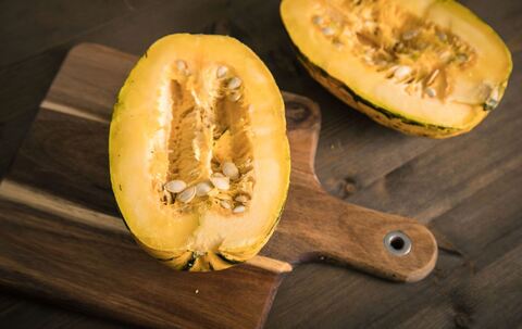 Ein aufgeschnittener Spaghetti-Kürbis liegt auf einem Brett