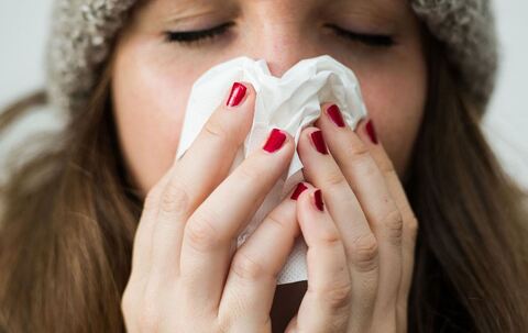 Frau hält sich ein Papiertaschentuch vor das Gesicht