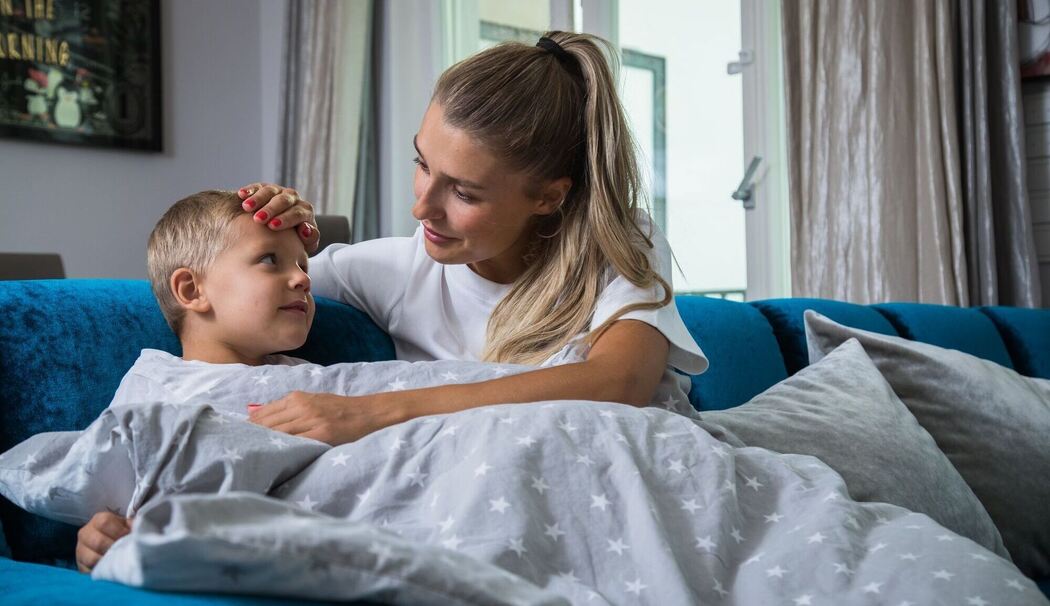 Eine Mutter legt ihre Hand auf die Stirn ihres Sohnes