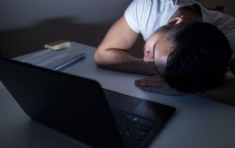 Mann legt erschöpft seinen Kopf auf den Tisch