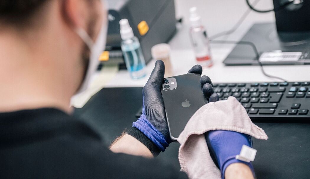 Ein Mitarbeiter überprüft ein refurbished Iphone