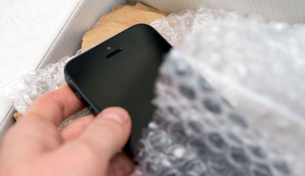 Person nimmt ein Smartphone aus einem Päckchen