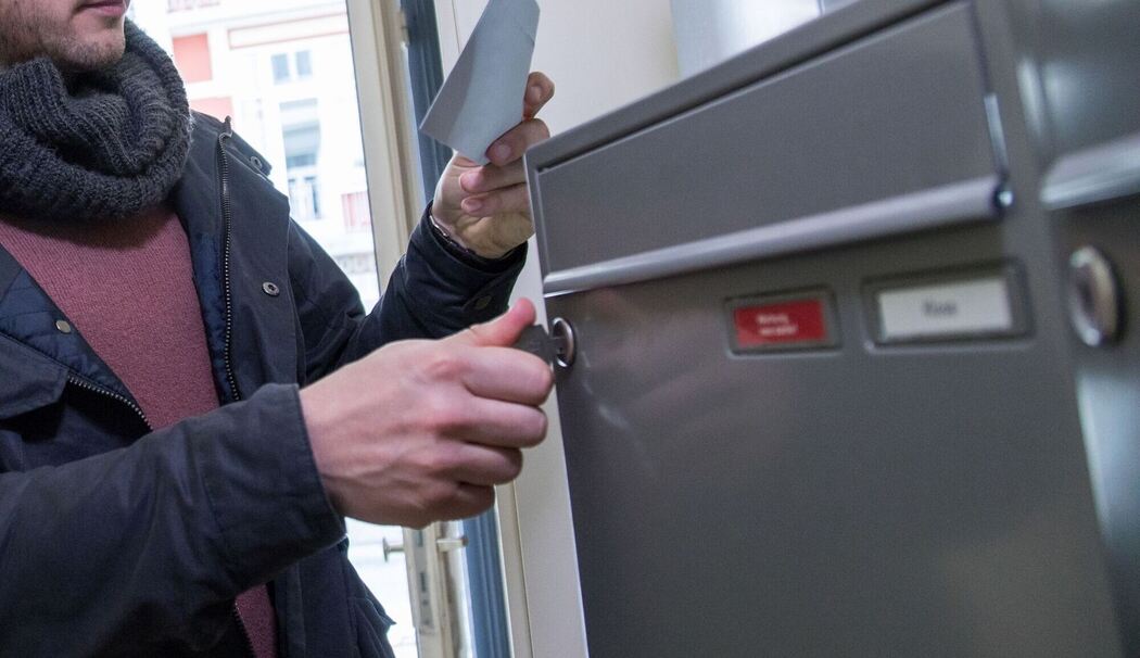 Ein Mann holt einen Brief aus dem Briefkasten