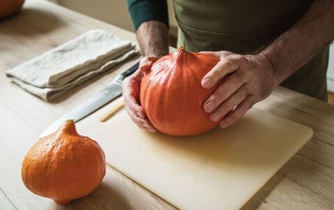 Ein Mann hält einen Hokkaido-Kürbis in den Händen